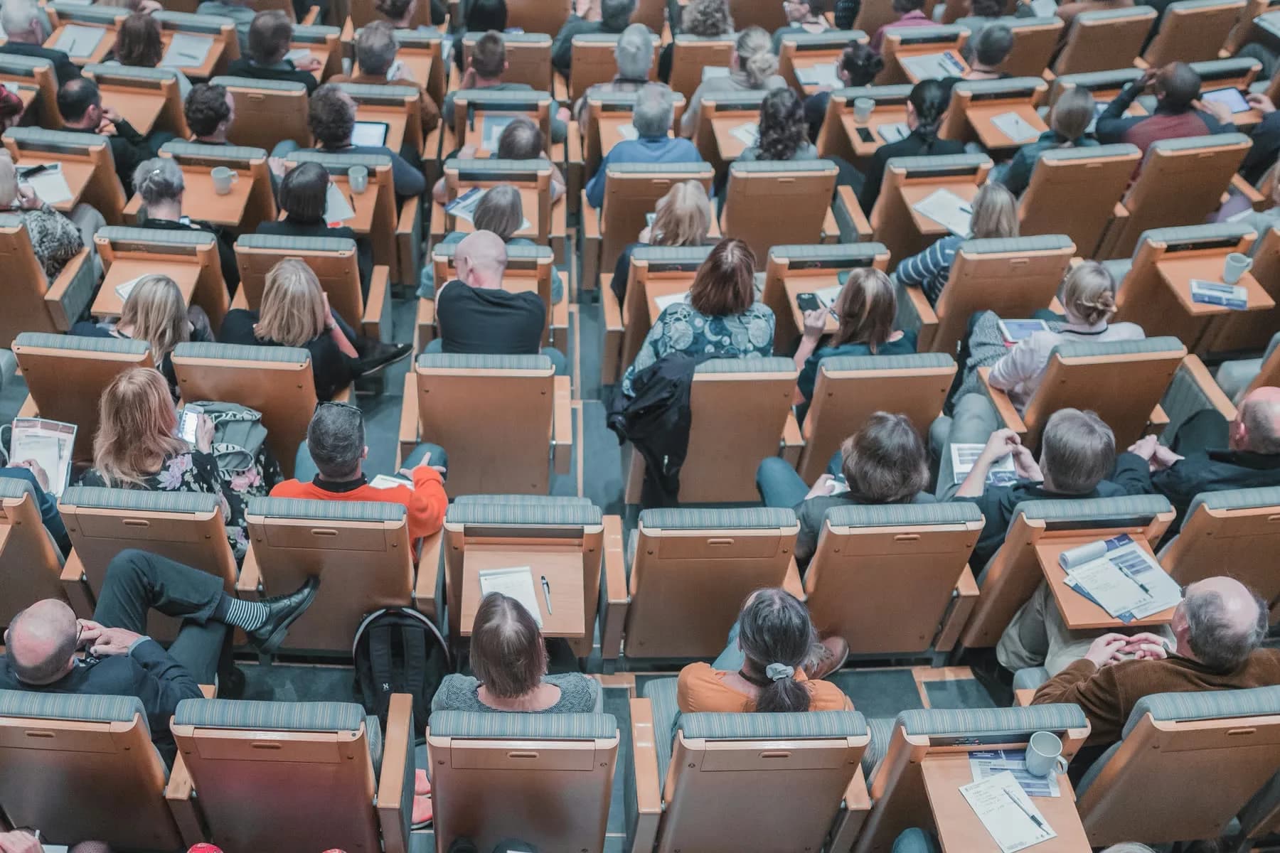 Collegezaal met oplopende rijen stoelen, een ruimte met een hoge bezetting en dus een hoge ventilatievraag